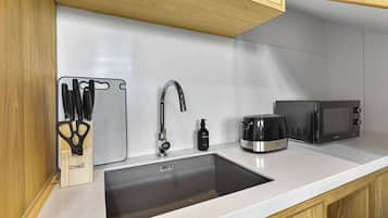 Een keuken met een roestvrijstalen spoelbak, een messenblok, een koffiezetapparaat en een magnetron.