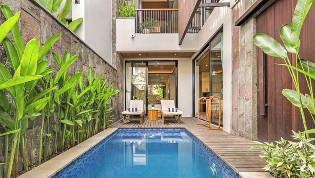 Une piscine avec une terrasse en bois, deux chaises longues et une petite table.