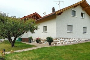 A two-story house with a stone foundation, a tiled roof, and a satellite dish. - E + E holiday apartment in Goggersreut (Röhrnbach)