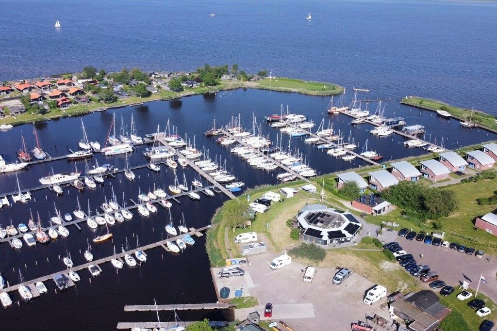 Een jachthaven met veel liggende boten, een centraal gelegen, rond gebouw en omliggende woongebouwen.