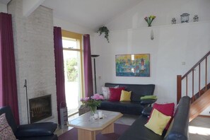 Ein Wohnzimmer mit Kamin, einer Couch, einem Couchtisch und einem Gemälde an der Wand.