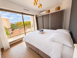 Ein Schlafzimmer mit einem großen Bett, einem Balkon und Blick sowie einer Deckenleuchte.
