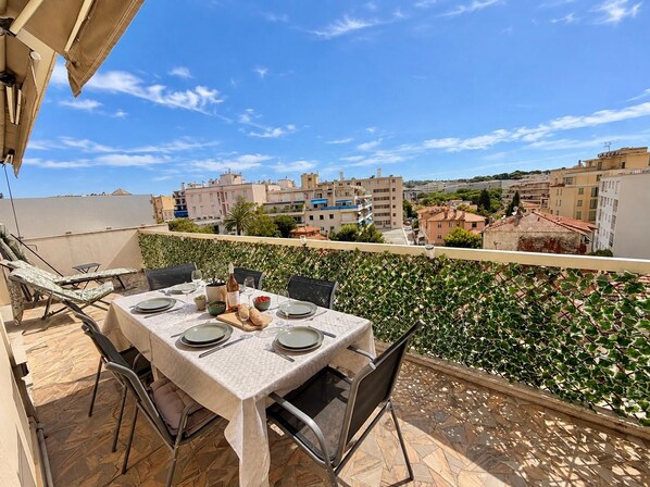 Eine Terrasse mit Esstisch, mit Blick auf eine Stadtlandschaft.