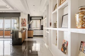 A modern kitchen with white cabinetry, a large window, and artwork on the walls. - The Zahra Collection: Newly Renovated  Luxury 2 Bedroom Marina&Spain Views (Tanger)
