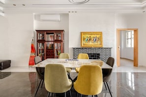 A dining area with a glass table, four chairs, a fireplace, and a painting on the wall. - The Zahra Collection: Newly Renovated  Luxury 2 Bedroom Marina&Spain Views (Tanger)