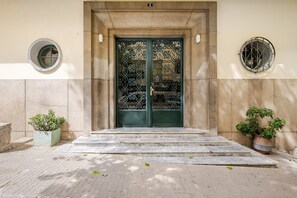 A building entrance with a green door, a small round window, and two potted plants. - The Zahra Collection: Newly Renovated  Luxury 2 Bedroom Marina&Spain Views (Tanger)
