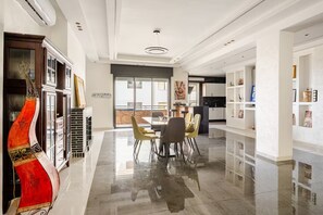 A modern dining area with a glass partition, a fireplace, and a view of the outdoors. - The Zahra Collection: Newly Renovated  Luxury 2 Bedroom Marina&Spain Views (Tanger)