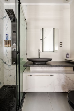 A modern bathroom with a glass-enclosed shower, a vessel sink, and a large mirror. - The Zahra Collection: Newly Renovated  Luxury 2 Bedroom Marina&Spain Views (Tanger)