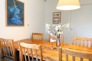Ein Essbereich mit einem Holztisch, Stühlen, einer Blumenvase und einem Bild an der Wand.
