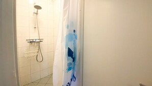 Une salle de bain avec une douche, un porte-serviettes et un rideau orné d’un motif bleu.