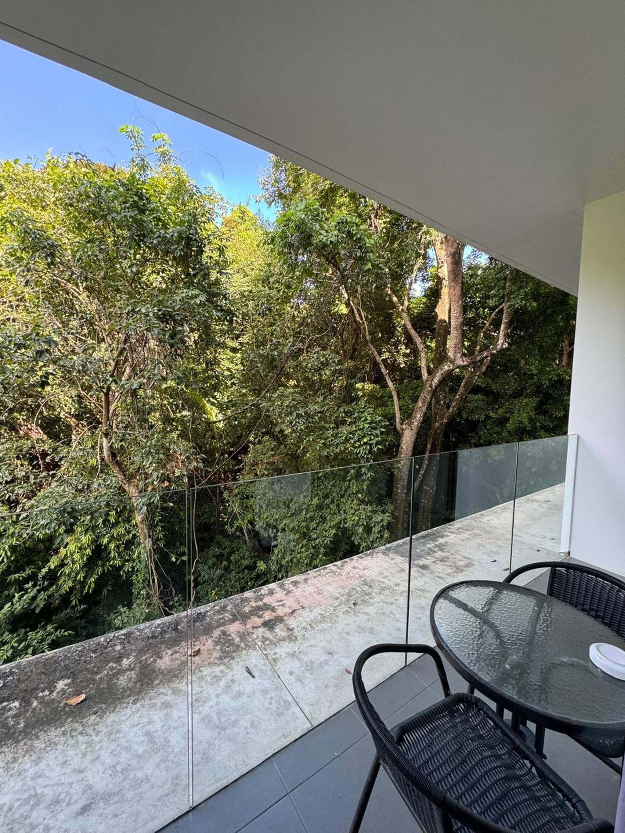 Un balcon doté d’une balustrade en verre, d’une table et de deux chaises.