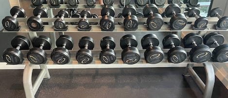 A gym with a rack of dumbbells and weight machines.