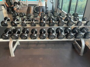 Un gimnasio con un banco de mancuernas y máquinas de pesas.