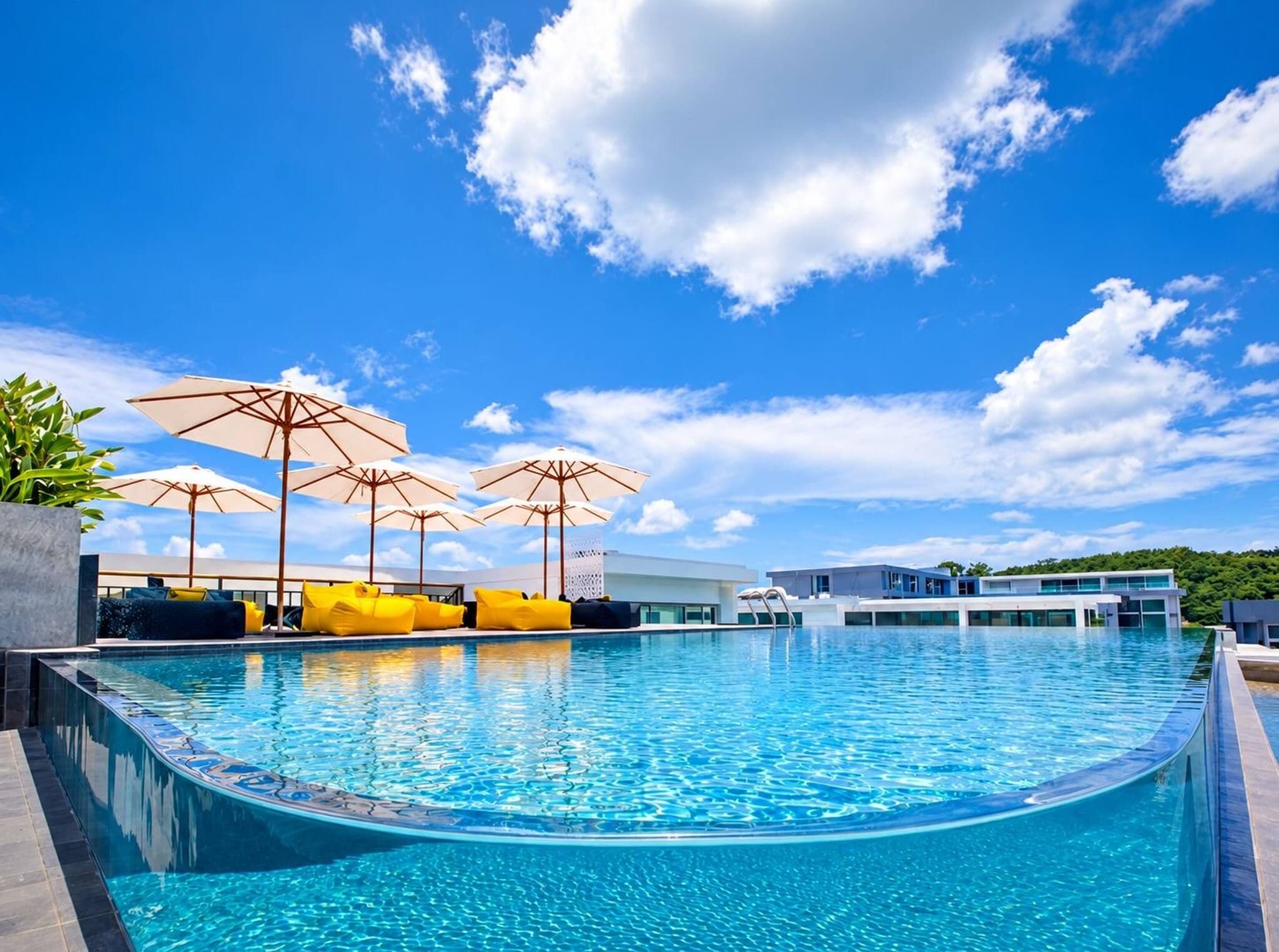 A swimming pool with lounge chairs and umbrellas, surrounded by modern buildings.