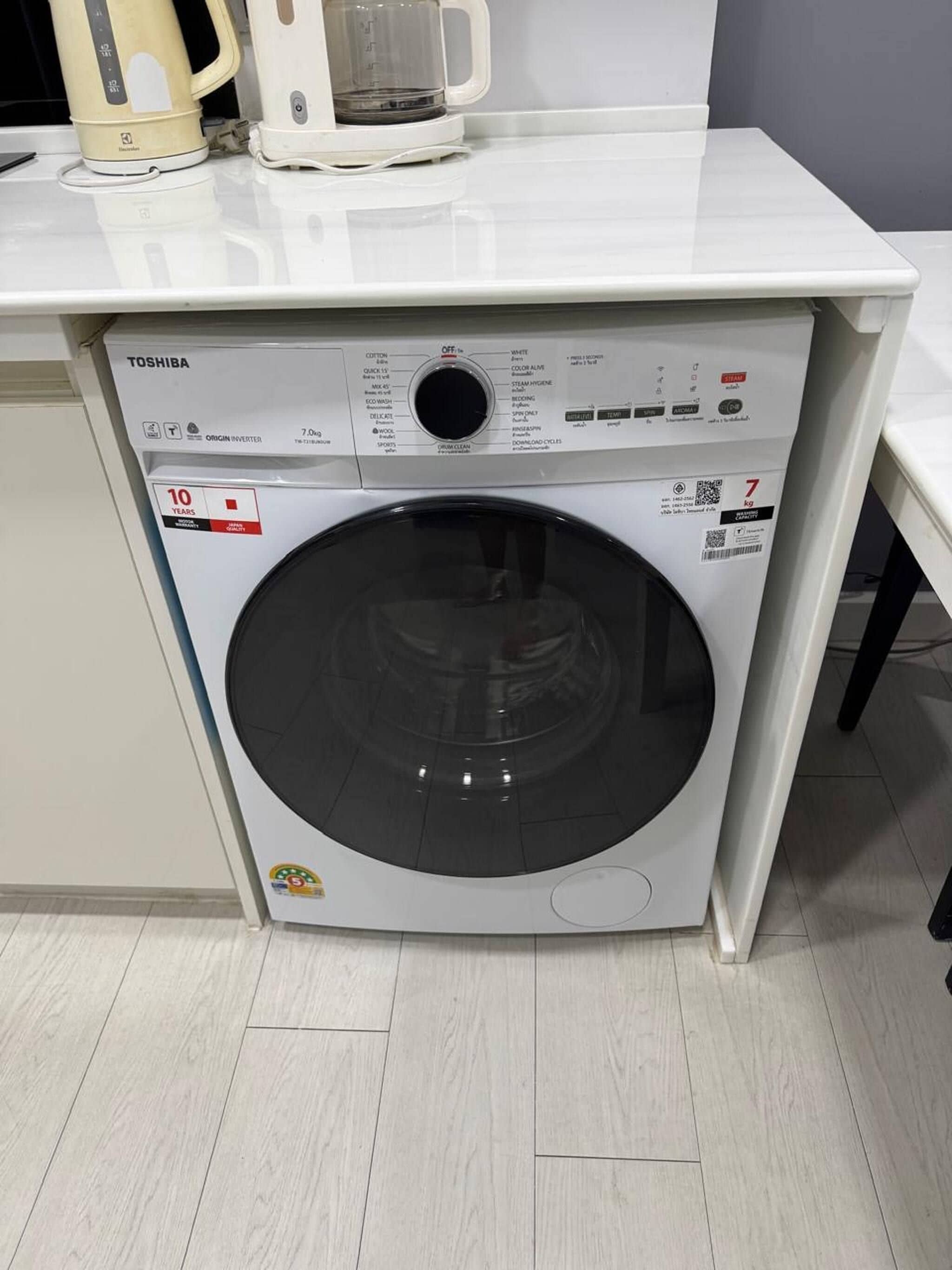 A compact washing machine with a control panel, placed in a small laundry area.