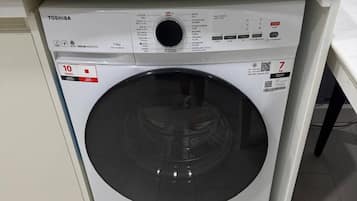 A compact washing machine with a control panel, placed in a small laundry area.