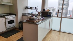A modern kitchen with a gas stove, oven, and a small island with a microwave. - Large Apartment, Hosts 2 -4 Adults/ Children.1-bedroom, 1 double Sofa bed. (Mexico)