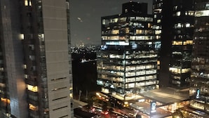 Een stadsgezicht 's nachts met moderne wolkenkrabbers, een rotonde en een goed verlichte kruising.