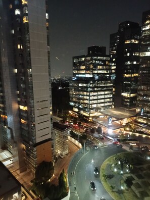 A nighttime cityscape with modern high-rise buildings, a roundabout, and a well-lit intersection. - Large Apartment, Hosts 2 -4 Adults/ Children.1-bedroom, 1 double Sofa bed. (Mexico)