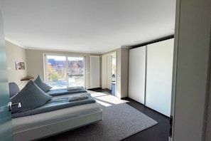 A modern bedroom with a bed, a view of the outdoors, and a sliding door. - Terrace apartment garden oasis (Lindau)