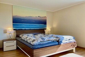 Ein Schlafzimmer mit einem Bett, Nachttischen und einem großflächigen Wandbild.