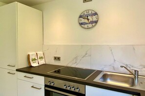 Eine Küche mit Einbauherd, Spüle und Wanduhr.