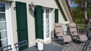Une terrasse avec une table et des chaises, un pot de fleurs et une rambarde.