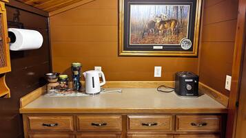 A kitchenette with a countertop, a kettle, a toaster, and a framed wildlife painting.