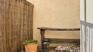 Un banc en bois, une plante en pot et une lanterne sur une terrasse en bois.