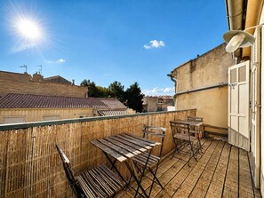 Un balcon doté de meubles en bois et offrant une vue sur les bâtiments voisins.