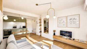 Ein modernes Wohnzimmer mit einer Couch, einem Couchtisch und einem Fernseher auf einem Holzboden.