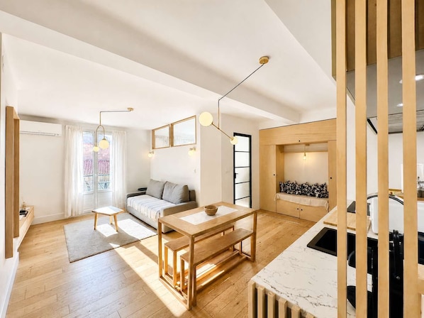 Un intérieur moderne avec un plancher en bois, un canapé, une table à manger et un coin cuisine.