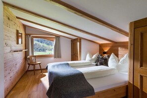 A bedroom with a bed, a chair, a window, and wooden walls. - in the Sunnbichl house (Hippach)