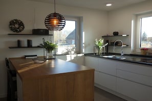A modern kitchen with a wooden island, pendant lighting, and a view of the outside. - Holiday home with 3 bedrooms (Poseritz OT Mellnitz-Hof)