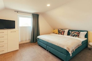 A bedroom with a bed, a television, a nightstand, and a window with curtains. - Holiday home with 3 bedrooms (Poseritz OT Mellnitz-Hof)