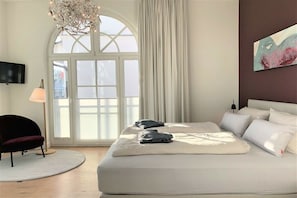 Una camera da letto con un letto grande, una poltrona rotonda, una lampada da terra e un quadro appeso al muro.