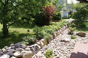 A garden with a stone pathway, various plants, and a bench. - Dat Fachwerkhus 1.OG (Ostseebad Trassenheide)
