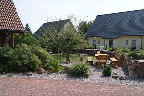 A courtyard with a patio area, stone walls, and a variety of plants. - Dat Fachwerkhus 1.OG (Ostseebad Trassenheide)