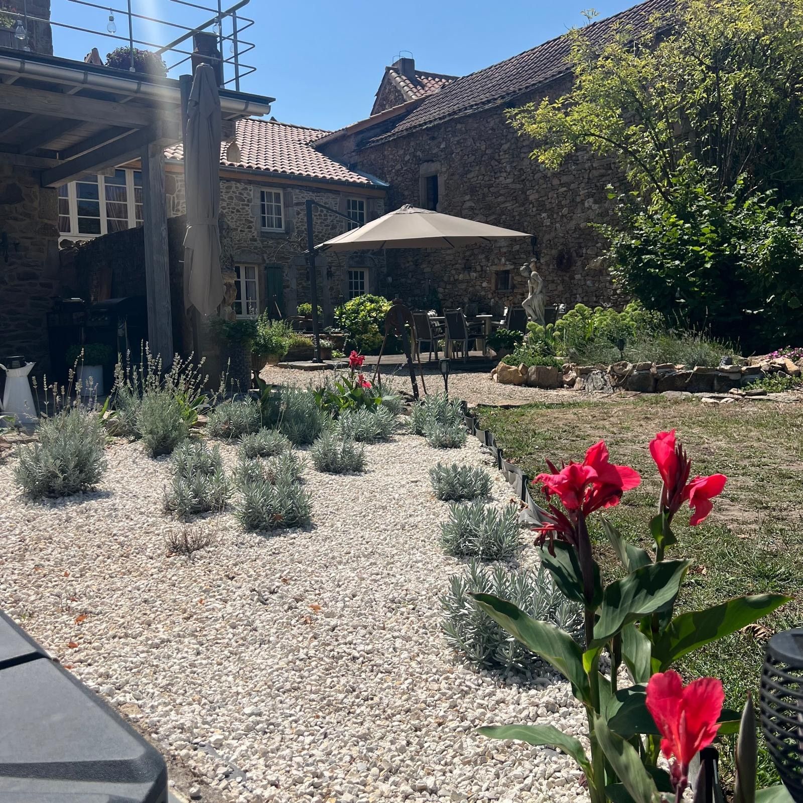 A courtyard with a stone building, outdoor seating, and a statue.