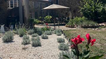 A courtyard with a stone building, outdoor seating, and a statue.