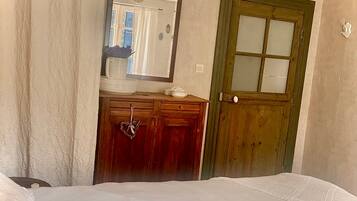 Una habitación con una cama, un aparador de madera, un espejo y una puerta verde.