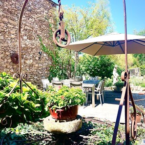 An outdoor patio with stone walls, a table with chairs, and a hanging umbrella.
