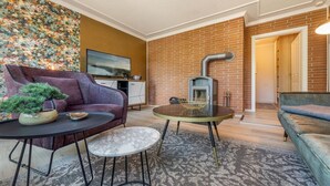 Ein Wohnzimmer mit einer Couch, einem kleinen runden Tisch, einer Topfpflanze und einem Kamin.