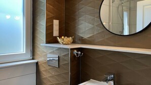 Ein Badezimmer mit Wandgestaltung in geometrischem Muster, einem runden Spiegel, einem Waschbecken und einem Handtuchhalter.