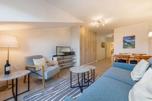 A modern living room with a sofa, armchair, coffee table, and a television. - Beach bliss at the Baltic Sea House (Binz)