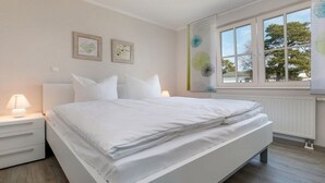 Une chambre à coucher avec un lit, une table de chevet, une lampe et une fenêtre avec des stores.