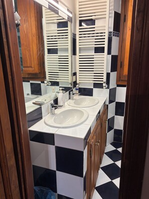 A bathroom with two sinks, a mirror, and a tiled floor. - House of the Hoopoe (Firenze)
