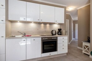 A modern kitchen with white cabinets, a stainless steel oven, and a coffee maker. - 5, Residence Dünenstraße (Binz)
