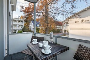 Ein Balkon mit Korbmöbeln, weißen Tassen und einem Kerzenständer.