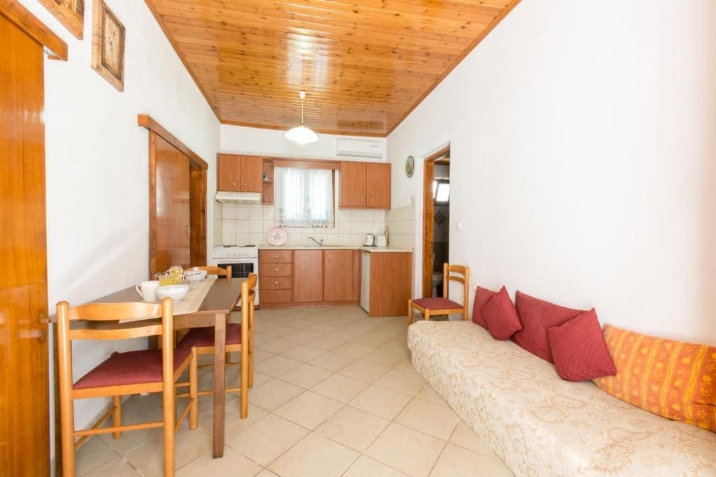 A compact living space with a dining area, kitchenette, and a sofa with cushions.